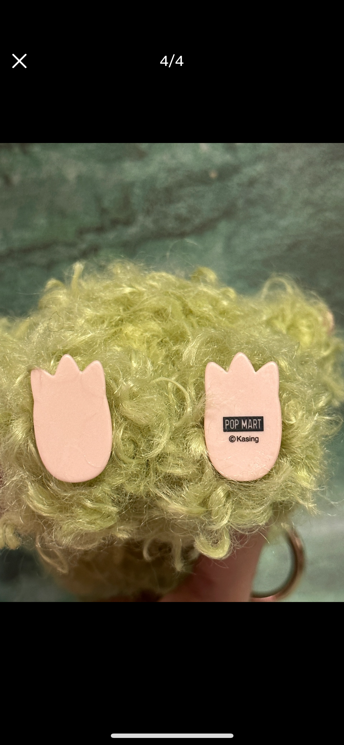 Close-up of a fluffy green object with pink cat-shaped earrings.