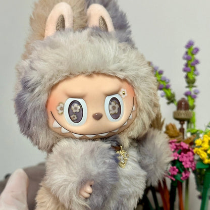 Plush toy with a furry hood resembling a creature, held by a person with a blurred background.