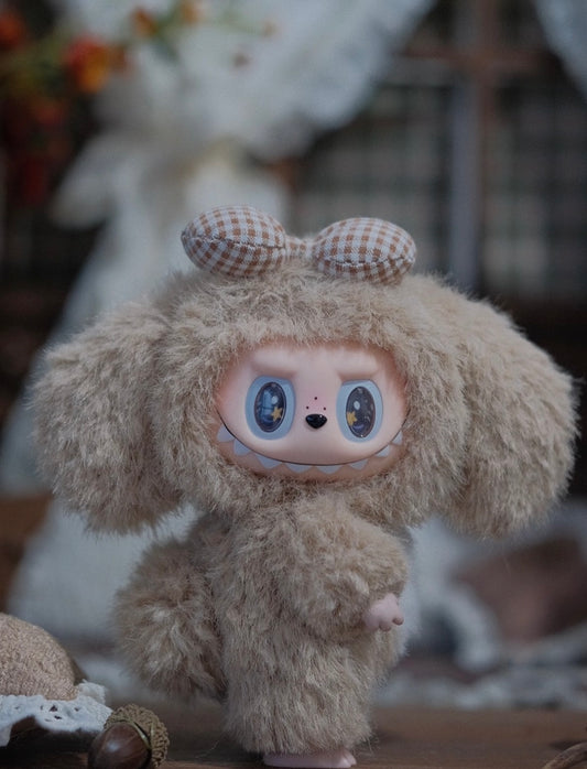 Plush toy with large eyes and a bow on its head, sitting on a surface with a blurred background.