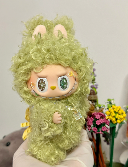 Green plush toy with bunny ears on a white surface with flowers in the background