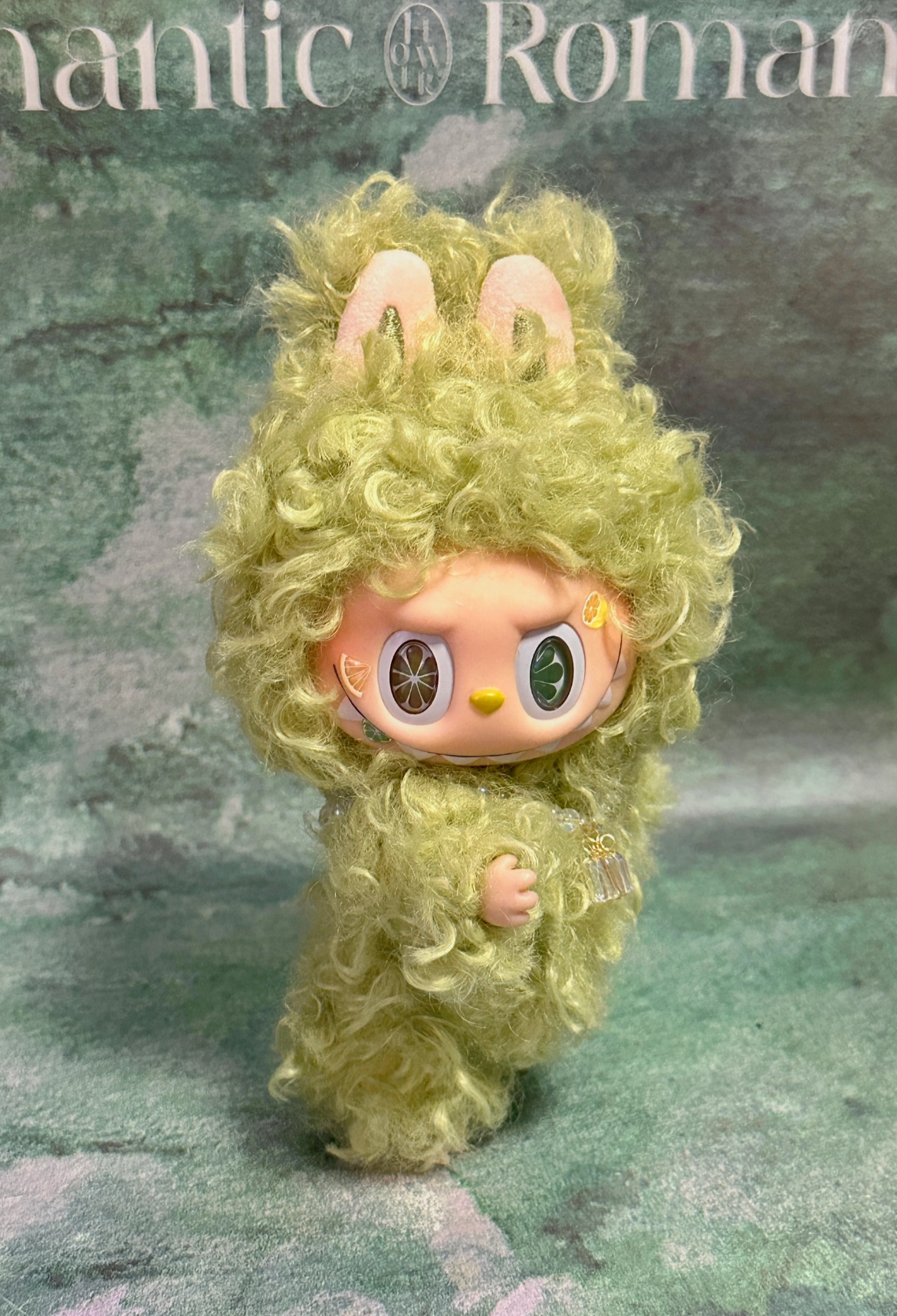 Toy figure with green hair and outfit on a textured background