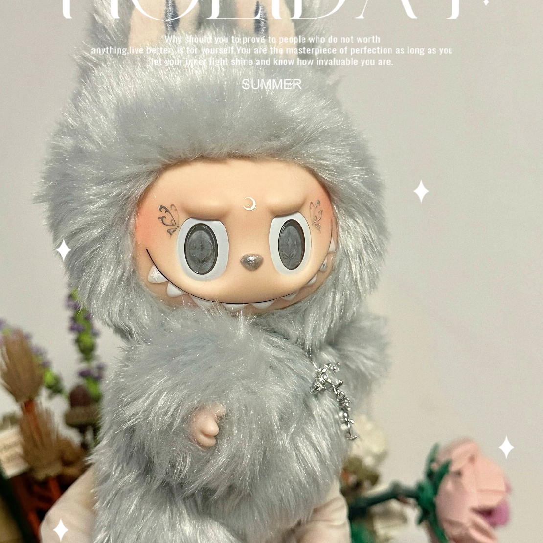 Plush toy with gray fur and large eyes on a light gray background with 'HOLIDAY' text.