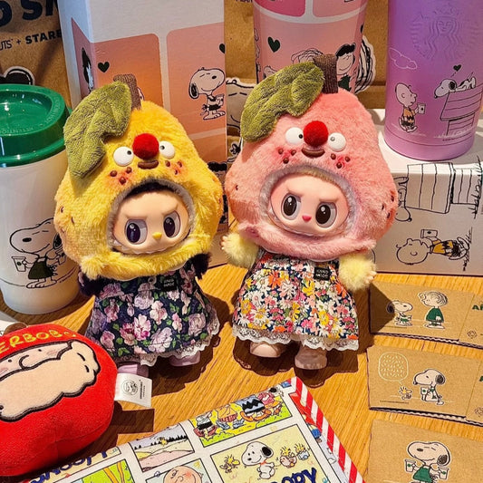 Two plush toys resembling a yellow character and a pink character with a flower on a wooden surface, surrounded by Starbucks products.